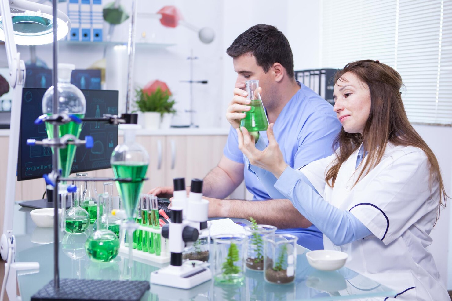 middle-age-woman-with-her-assistant-working-research-lab-microbiology-test-tubes_482257-34452